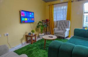 - un salon avec un canapé, une chaise et une télévision dans l'établissement Nash Issah Green- Milimani Nakuru-1Bedroom, à Nakuru