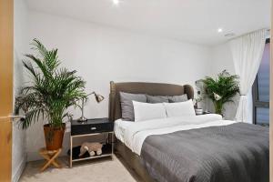 um quarto com uma cama e dois vasos de plantas em 2 Bedroom flat near shops and restaurants em Londres