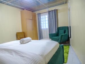 - une chambre avec un lit et une chaise verte dans l'établissement Nash Issah Green- Milimani Nakuru-1Bedroom, à Nakuru