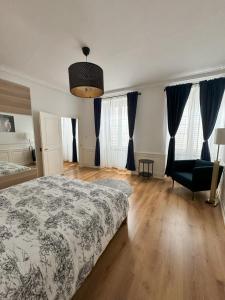 a bedroom with a bed and a chair and windows at Magnifique appart côté Cathédrale in Strasbourg