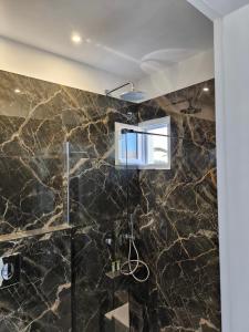 bagno con doccia e pareti in marmo nero di Mary Rooms a Perivolos Altre 27 foto