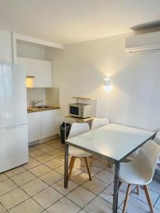eine Küche mit einem Tisch und Stühlen sowie einem Kühlschrank in der Unterkunft Résidence Graziella Studio 301 in Juan-les-Pins