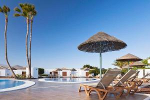 un gruppo di sedie e ombrelloni accanto alla piscina di Sunny Daze Golf del Sur a San Miguel de Abona