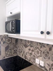 a kitchen with white cabinets and a microwave at La Deauvillaise - Résidence du Golf in Deauville