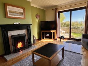 a living room with a fireplace and a tv at 4 Bedroom Detached Farmhouse Mountain Views in Beaumaris