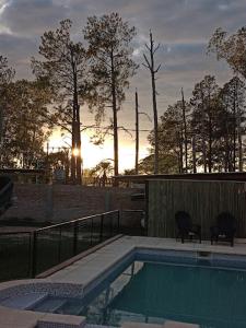 una piscina con 2 sillas y una puesta de sol en el fondo en Cabaña Lo De Leo en Concordia