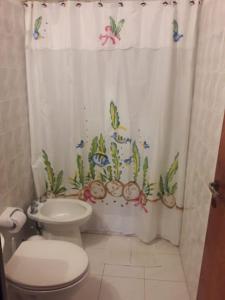 y baño con aseo y cortina de ducha. en Cabaña Lo De Leo en Concordia