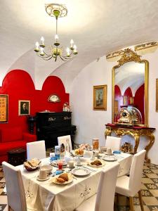 uma sala de jantar com uma mesa com cadeiras brancas e paredes vermelhas em B&B Palazzo Lombardi em Lucera