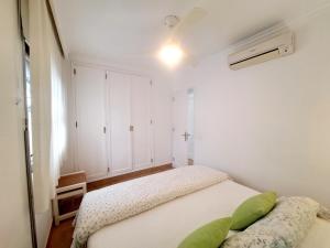Un dormitorio con una cama con almohadas verdes. en Precioso bungalow en Maspalomas, en San Bartolomé