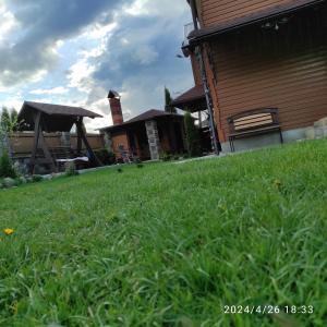 a grassy yard with a bench in front of a house at Zatushok pid goroyu in Verkhovyna