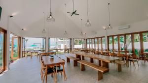 a cafeteria with wooden tables and chairs and windows at Rejuvenate Resort and Restaurant in Jembrana