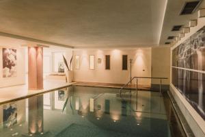 einen Pool in einem Raum mit Gemälden an der Wand in der Unterkunft Hotel Mühlbacherhof in Algund