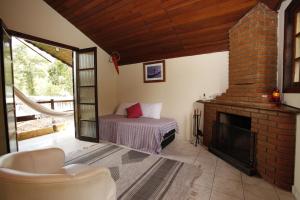 a living room with a fireplace and a bed at Apoena Chales da Ilha in São Francisco Xavier