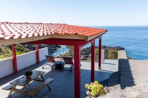 einen Pavillon mit einem Tisch, einer Bank und dem Meer in der Unterkunft Cantinho dos Cagarros in Lajes do Pico