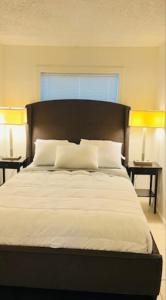 een slaapkamer met een groot bed met witte lakens en kussens bij Perfect relaxing A 12 mn from the beach free parking in West Palm Beach