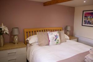 バンフにあるButtermere Cottageのベッドルーム1室(白いシーツと枕のベッド1台付)