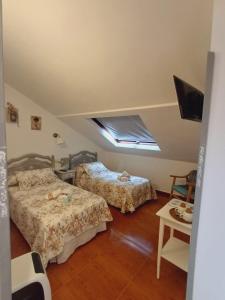 a bedroom with two beds and a television in it at Hotel Apartamentos El Coterin in Arenas de Cabrales
