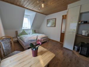 Un dormitorio con una cama y una mesa con un jarrón de flores en Ferienwohnungen Langer, en Stadt Wehlen