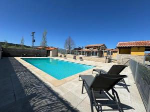 a swimming pool with two chairs next to a house at Complejo Rural Los Cachos in Baterna