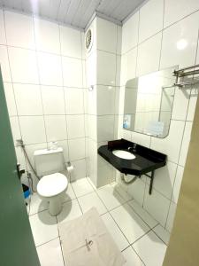 a white bathroom with a toilet and a sink at Borges Hotel in Imperatriz