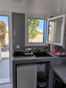 a kitchen with a sink and two windows at Mary Rooms in Perivolos