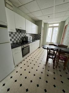 - une cuisine avec des placards blancs, une table et des chaises dans l'établissement Aquanerius Résidence, à Néris-les-Bains