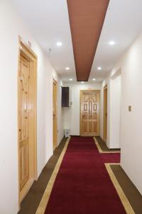 a corridor with a red carpet and wooden doors at Vantage Lodge in Skardu