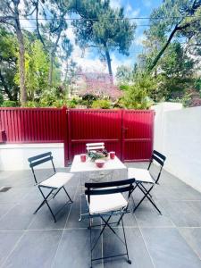 een patio met een tafel en stoelen en een rood hek bij Krystel Avel à La baule in La Baule