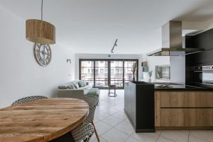 eine Küche und ein Wohnzimmer mit einem Holztisch im Zimmer in der Unterkunft Stylish two bedroom apartment on top location in Middelkerke