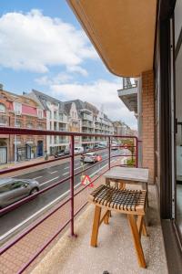eine Bank auf einem Balkon mit Straßenblick in der Unterkunft Stylish two bedroom apartment on top location in Middelkerke