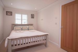 a bedroom with a bed with white sheets and a window at Chy An Gweal Farm Coach House in Carbis Bay