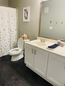 a bathroom with a toilet and a sink and a mirror at Elegant 3-Bedroom Condo in Lewes with Pond Views in The Plantations +18 photos