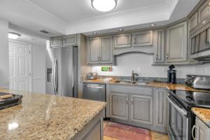 a kitchen with gray cabinets and a stainless steel refrigerator at FL-Seaspray Perdido Key 605 condo in Pensacola