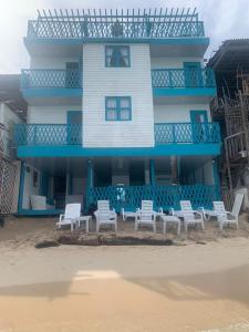 普拉亞布蘭卡的住宿－Cabaña Balcones del Mar，海滩上一座建筑前面有白色椅子