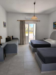 a bedroom with two beds and a desk and a window at Mary Rooms in Perivolos