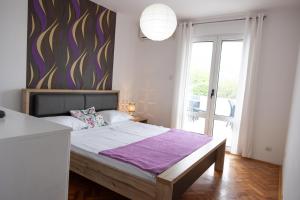 sypialnia z dużym łóżkiem i fioletowym kocem w obiekcie Apartmani Novkovic w Barze