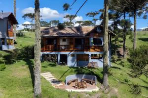 une maison avec un balcon et une cour avec des palmiers dans l'établissement Chalé Urubici - Morada nas Montanhas, à Urubici