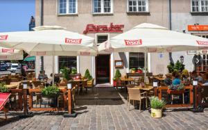 un restaurante con mesas y sombrillas frente a un edificio en BaySide Apartments Center City, en Gdansk