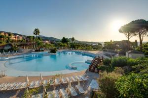 a large swimming pool with lounge chairs in a resort at Studio cabine climatisé vue golf à Cap Estérel in Saint-Raphaël