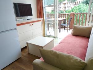 a living room with a couch and a television and a balcony at Studio cabine climatisé vue golf à Cap Estérel in Saint-Raphaël