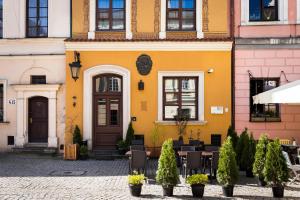 un edificio amarillo con mesas y sillas en un patio en Apartamenty Kamienica Muzyków Old Town Lublin, en Lublin