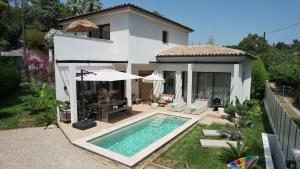 a villa with a swimming pool in front of a house at Superbe Villa très proche cannes in Mougins