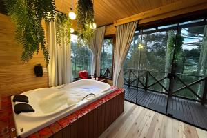 una grande vasca da bagno in una camera con balcone di Chalé O Canto da Araponga a Águas Brancas Altre 73 foto
