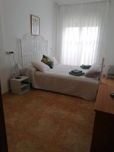 a bedroom with a large white bed with a window at Lodosol in Lo Pagán