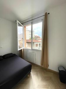 a bedroom with a bed and a large window at DUPLEIX PARISIEN in Vanves