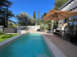 a swimming pool with an umbrella next to a house at Superbe Villa très proche cannes in Mougins