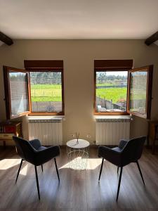 une chambre avec deux chaises, une table et deux fenêtres dans l'établissement Casa Bieiteiro, à Valdoviño