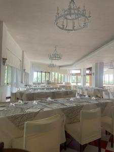 ヴィッランマレにあるHotel Royalのダイニングルーム(白いテーブル、椅子、シャンデリア付)