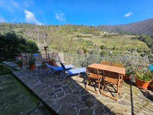 un patio con mesa, sillas y una colina en Il Bassotto - Homy 5 Terre, en Volastra
