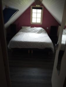 een bed in een rode slaapkamer met een raam bij L'ECUREUIL in Loc-Envel